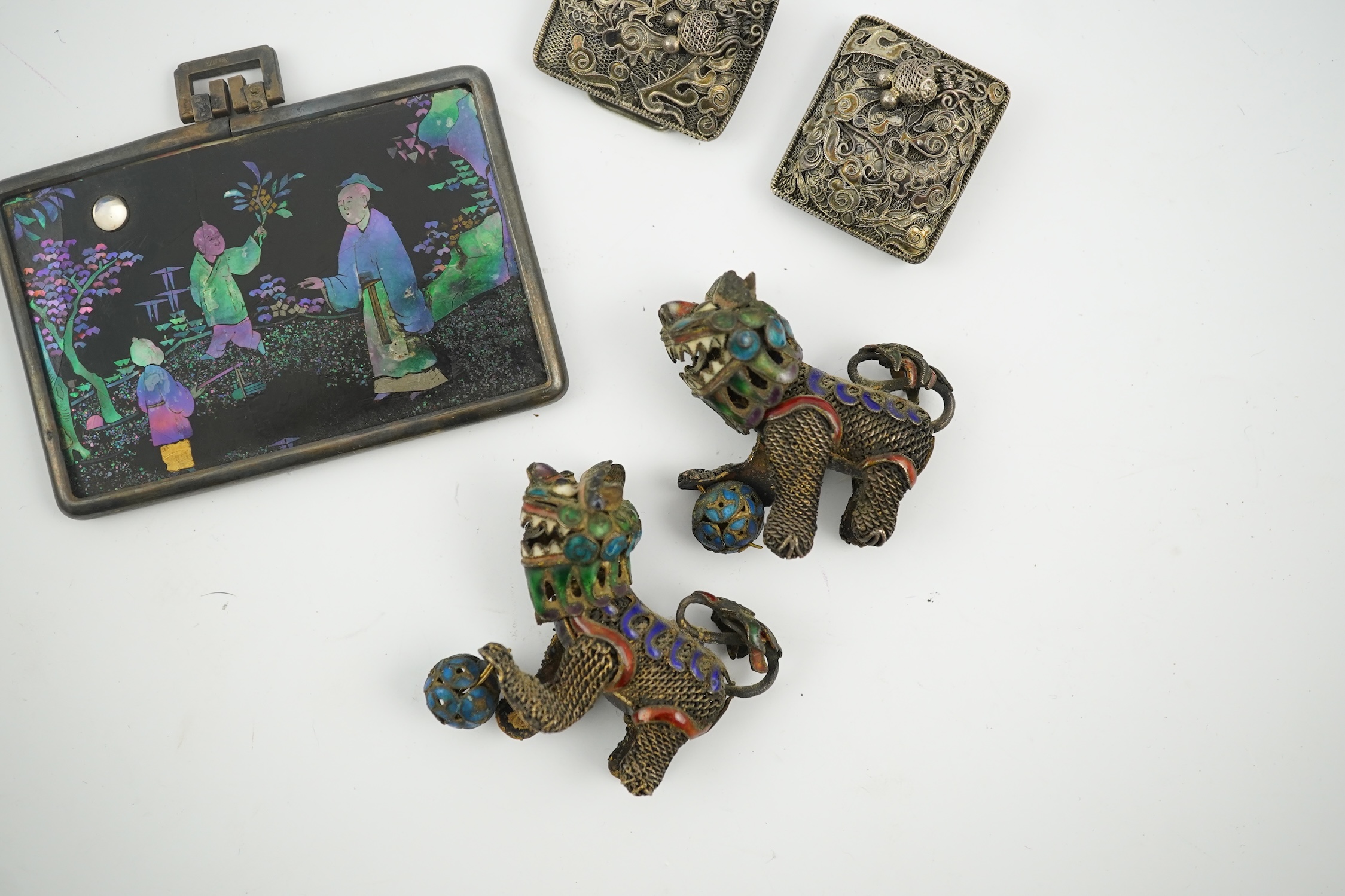 A Chinese silver buckle with filligree butterfly decoration, a pair of enamelled miniature lion dogs with balls and a small lac burgaute panel. Lion dogs 4.5cm long. Condition - good